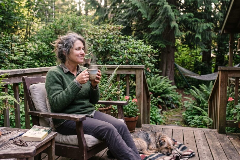 A person sitting outside in soft morning light with a warm drink, unhurried and at ease.